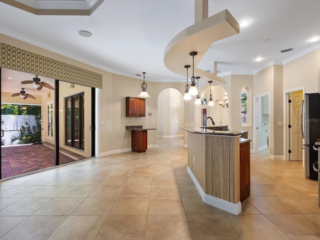 kitchen featuring plenty of natural light, crown molding, light tile patterned floors, decorative light fixtures, and stainless steel refrigerator