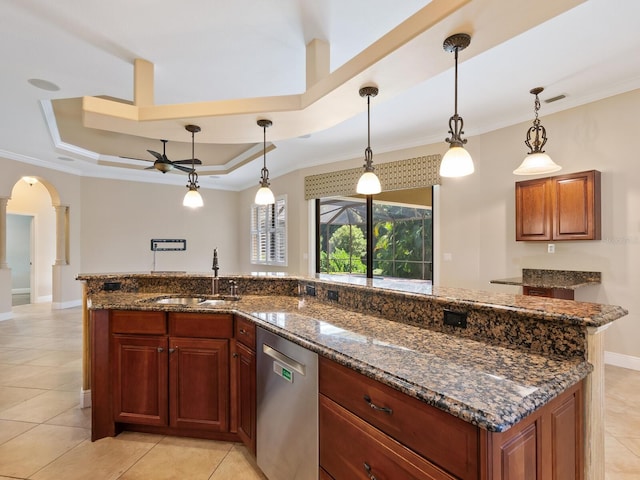 kitchen with stainless steel dishwasher, a raised ceiling, sink, pendant lighting, and dark stone countertops