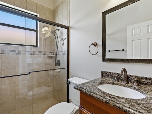 bathroom with vanity, toilet, and a shower with door