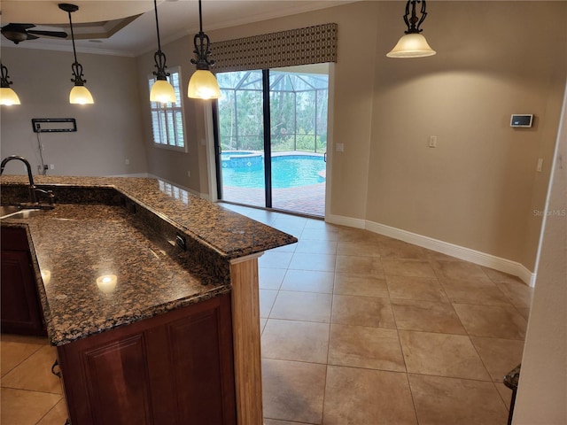 kitchen featuring hanging light fixtures, crown molding, sink, and dark stone counters