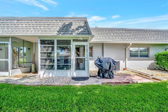 back of property with a sunroom and a yard