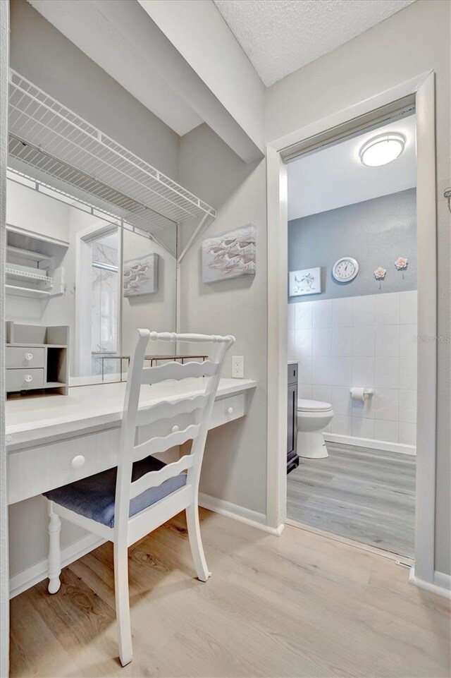 interior space with tile walls, toilet, hardwood / wood-style floors, and a textured ceiling