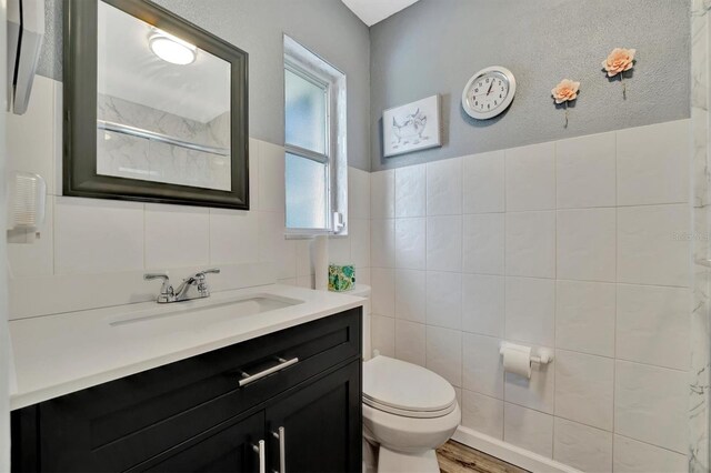 bathroom featuring vanity, toilet, hardwood / wood-style floors, and tile walls