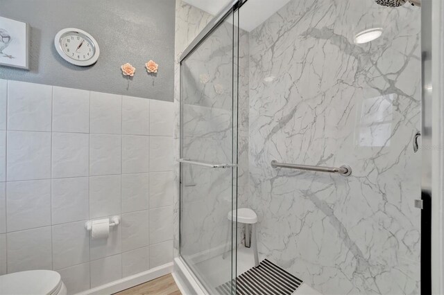 bathroom with toilet, hardwood / wood-style flooring, and walk in shower