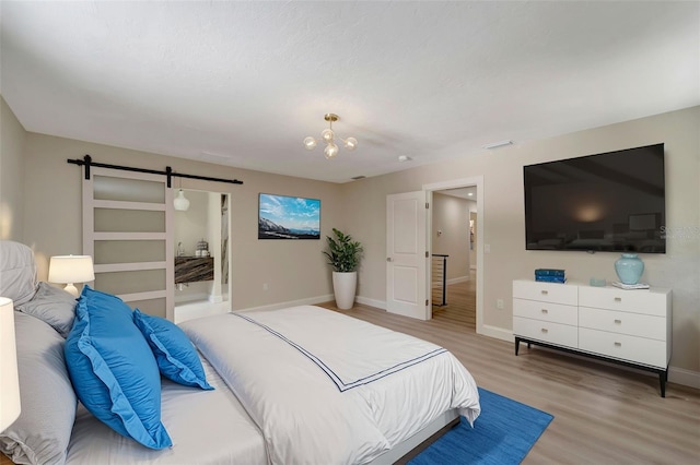 bedroom featuring an inviting chandelier, a barn door, and hardwood / wood-style floors