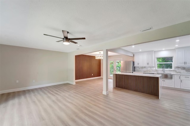 kitchen featuring a kitchen island, stainless steel fridge, a healthy amount of sunlight, and white cabinetry