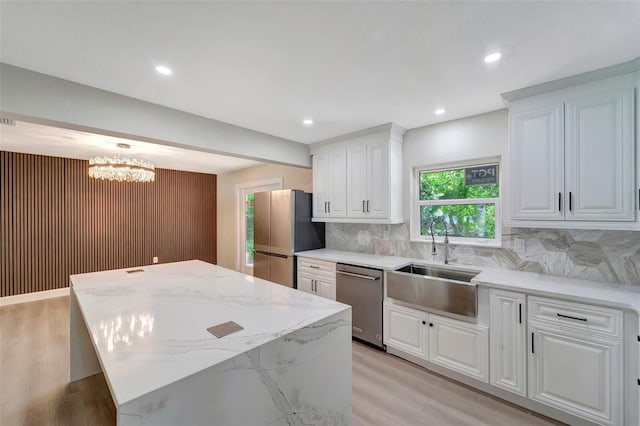 kitchen with white cabinets, sink, tasteful backsplash, stainless steel appliances, and a center island