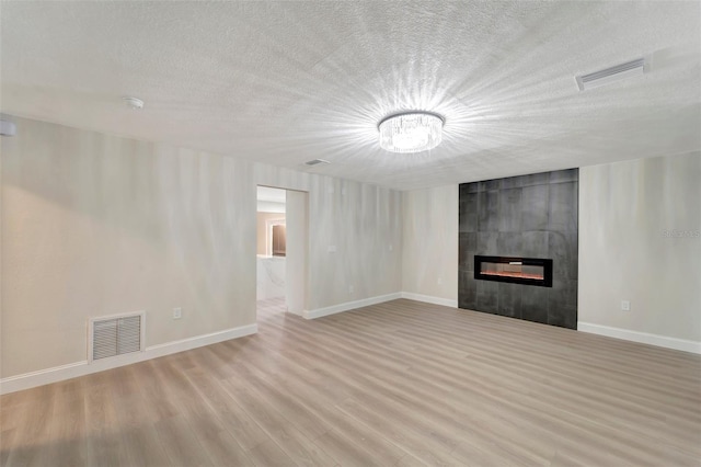 unfurnished living room featuring a textured ceiling, light hardwood / wood-style flooring, and a large fireplace