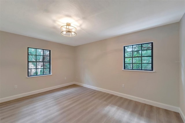 empty room with an inviting chandelier, light hardwood / wood-style floors, and a wealth of natural light