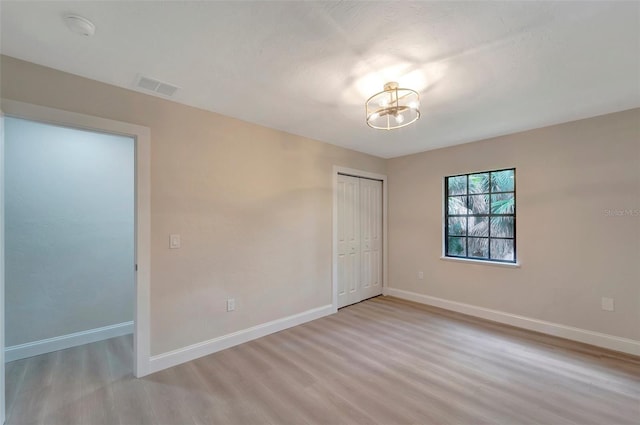 unfurnished room with a notable chandelier and light hardwood / wood-style flooring