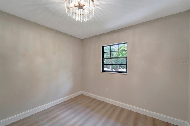 unfurnished room with wood-type flooring and a chandelier