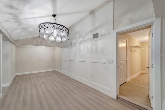 unfurnished dining area featuring a textured ceiling and light hardwood / wood-style flooring