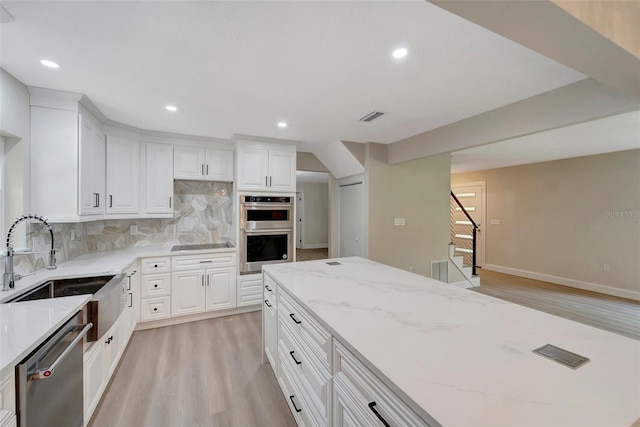 kitchen featuring light hardwood / wood-style floors, sink, white cabinetry, stainless steel appliances, and light stone countertops