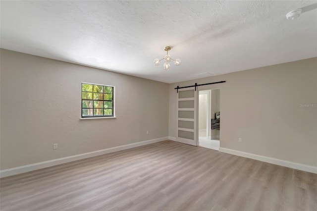 spare room featuring a textured ceiling, light wood-type flooring, and a barn door