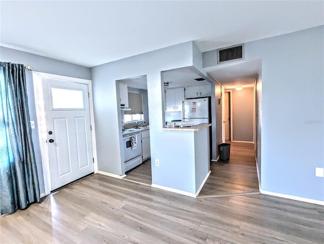 kitchen with stainless steel fridge, hardwood / wood-style flooring, white range with electric stovetop, and sink