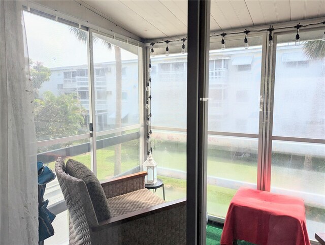 sunroom with wooden ceiling, a water view, and a healthy amount of sunlight