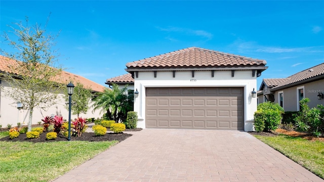 mediterranean / spanish home with a garage, decorative driveway, a tile roof, and stucco siding