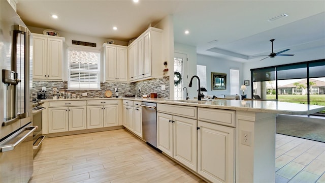 kitchen featuring ceiling fan, sink, white cabinetry, backsplash, and kitchen peninsula