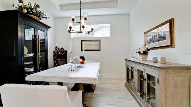 dining room with a tray ceiling, light hardwood / wood-style floors, and an inviting chandelier