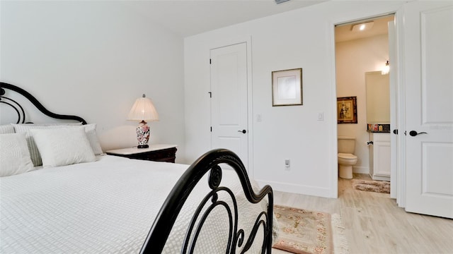 bedroom with ensuite bathroom and light hardwood / wood-style floors