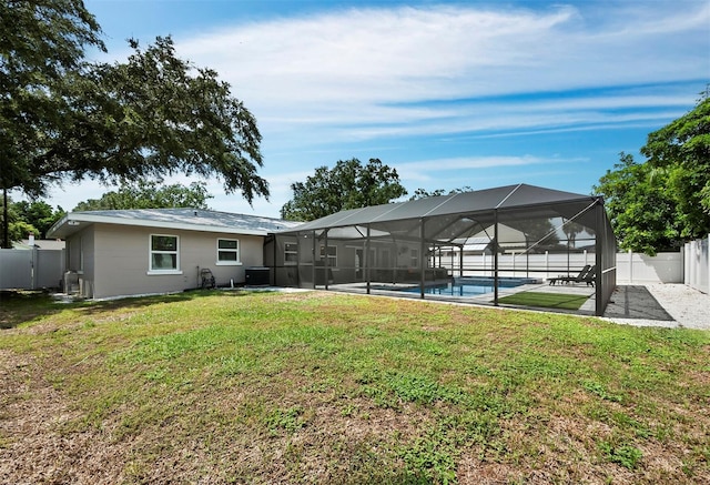 rear view of house featuring glass enclosure, a yard, and a patio