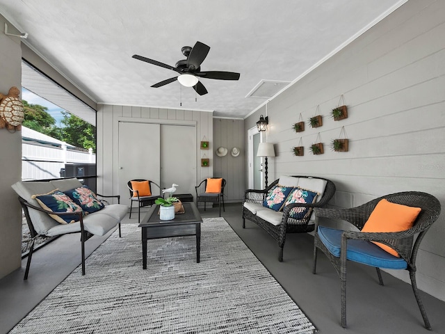 interior space featuring concrete flooring, ceiling fan, wooden walls, and ornamental molding