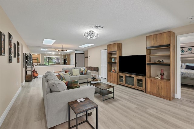 living room featuring a textured ceiling, an inviting chandelier, and light wood-type flooring