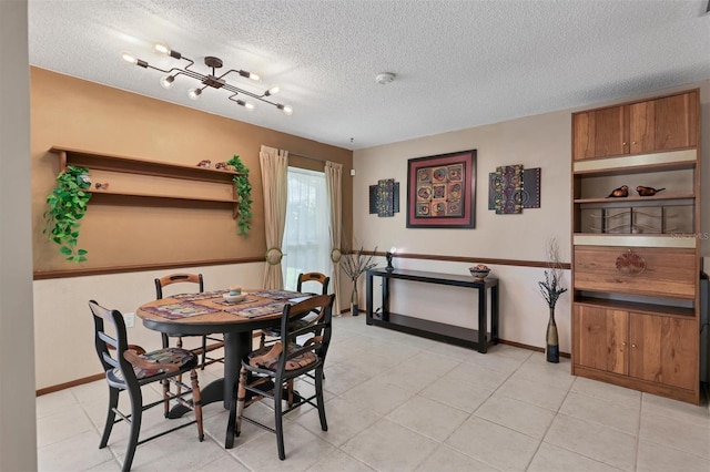 dining area featuring a textured ceiling, baseboards, and a chandelier