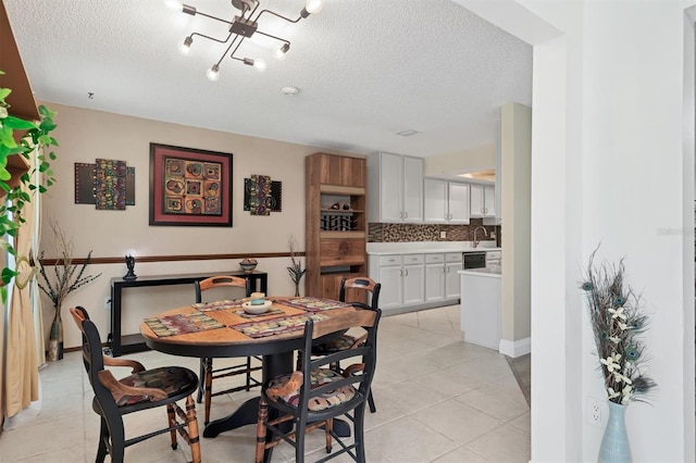 dining area featuring a textured ceiling, light tile patterned floors, a chandelier, and baseboards
