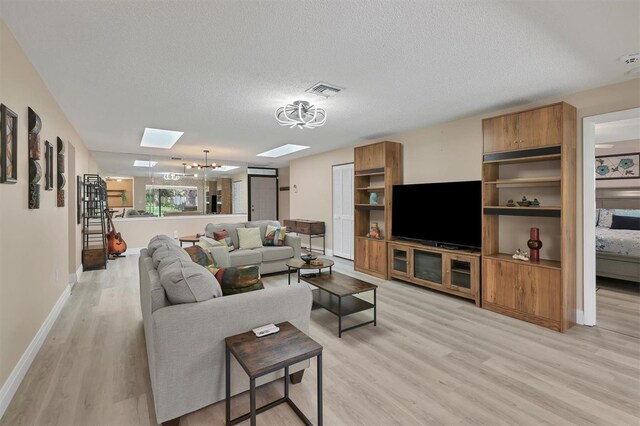 3541 Wilkinson Woods Dr Unit 40, Sarasota, FL 34231 - living room with a skylight, light wood-type flooring, a textured ceiling, and a chandelier