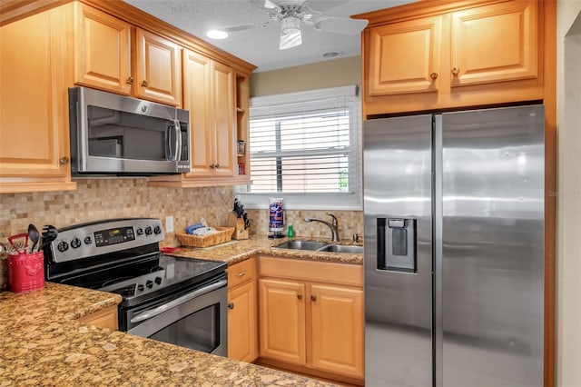 kitchen with stainless steel appliances, sink, decorative backsplash, ceiling fan, and light stone counters