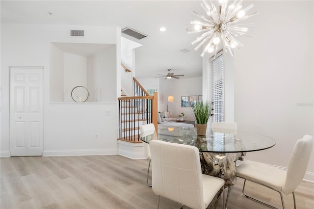 dining area with ceiling fan with notable chandelier and light hardwood / wood-style flooring