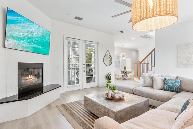 living room with light wood-type flooring and ceiling fan with notable chandelier