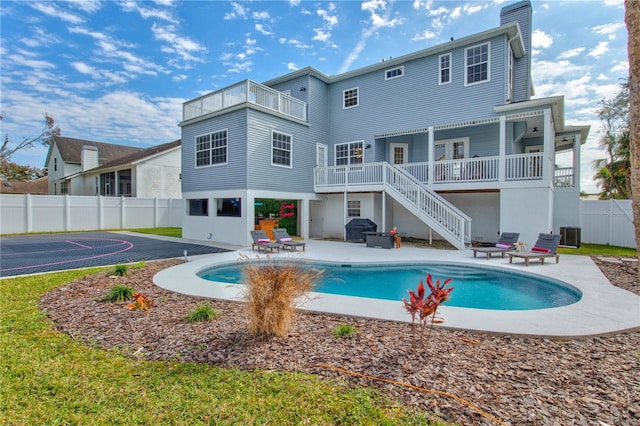 rear view of house with a fenced in pool and a patio