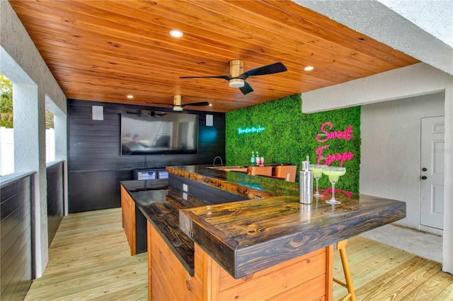 kitchen with light wood-type flooring, ceiling fan, wooden walls, and wooden ceiling