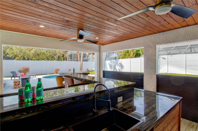 exterior space featuring ceiling fan, a fenced in pool, and sink