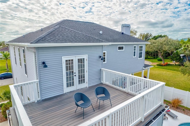 rear view of house with a wooden deck, a lawn, and french doors