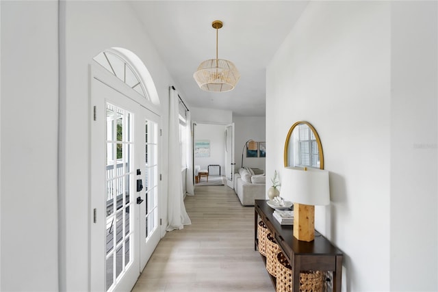 entryway featuring light wood-type flooring, french doors, and an inviting chandelier