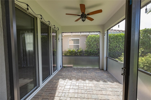 unfurnished sunroom featuring ceiling fan and a wealth of natural light