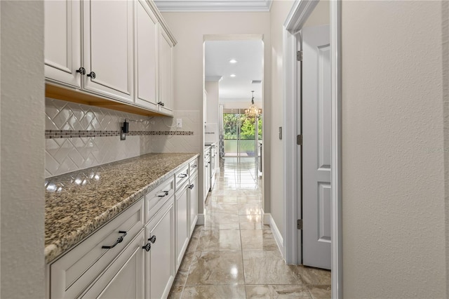 kitchen with crown molding, white cabinetry, stone countertops, and tasteful backsplash