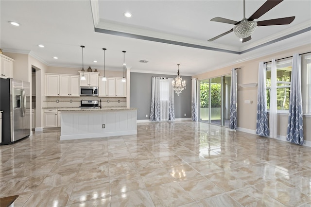 kitchen with pendant lighting, an island with sink, stainless steel appliances, ceiling fan with notable chandelier, and crown molding