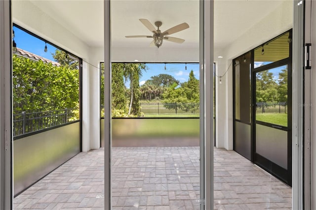 unfurnished sunroom featuring ceiling fan