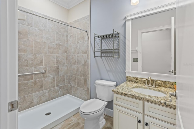 bathroom with a tile shower, vanity, crown molding, and toilet