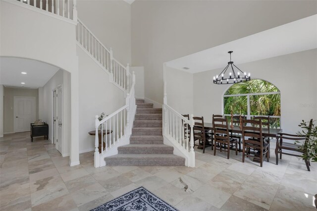 staircase with a notable chandelier and a towering ceiling