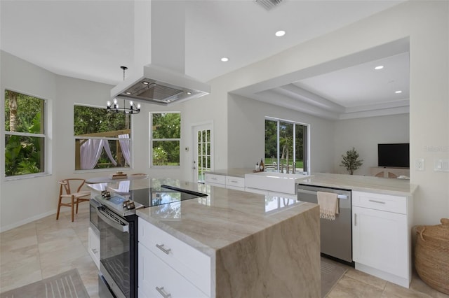 kitchen with island exhaust hood, a center island, stainless steel appliances, white cabinetry, and light stone counters