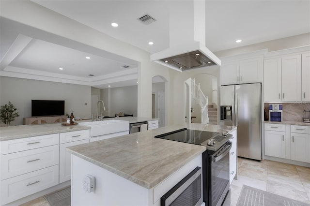 kitchen with white cabinets, stainless steel appliances, sink, a kitchen island, and island range hood