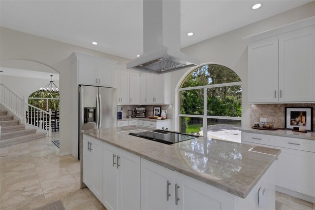 kitchen with light stone countertops, tasteful backsplash, island exhaust hood, white cabinetry, and black electric stovetop