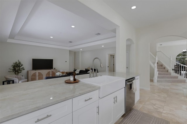 kitchen with white cabinets, light stone countertops, sink, a tray ceiling, and stainless steel dishwasher