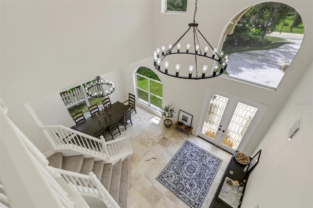 foyer entrance with a towering ceiling, french doors, and a notable chandelier