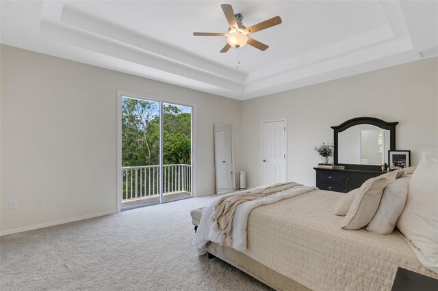 carpeted bedroom with a tray ceiling, ceiling fan, and access to outside